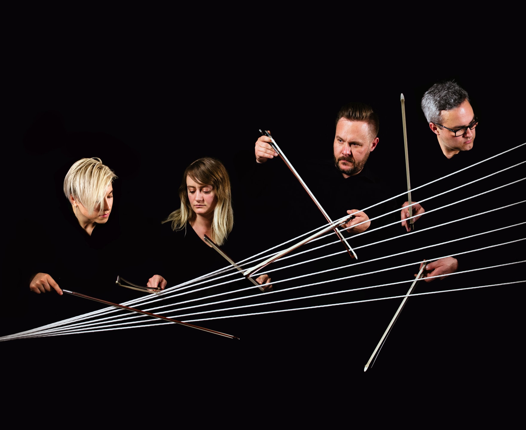 4 members of Spektral Quartet hold up their bows against lines that form a spectrum